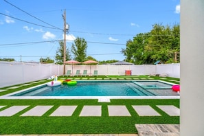 A backyard with a swimming pool, artificial grass, and a fenced area. - Luxe Villa • Pool&Spa • Sauna • Games • Sleeps 20+ (Tampa)