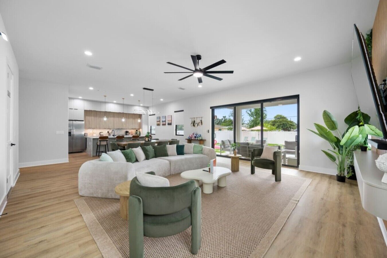 A modern living room with a sectional sofa, a coffee table, and a dining area with a kitchen in the background.