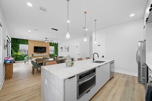 A modern kitchen with a central island, built-in oven, and a dishwasher. - Luxe Villa • Pool&Spa • Sauna • Games • Sleeps 20+ (Tampa)