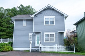 A two-story house with a white picket fence, a front door, and a small porch. - Ski View Summit (Gatlinburg)
