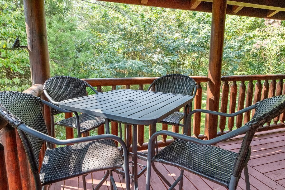 A covered outdoor deck with a table and four chairs.