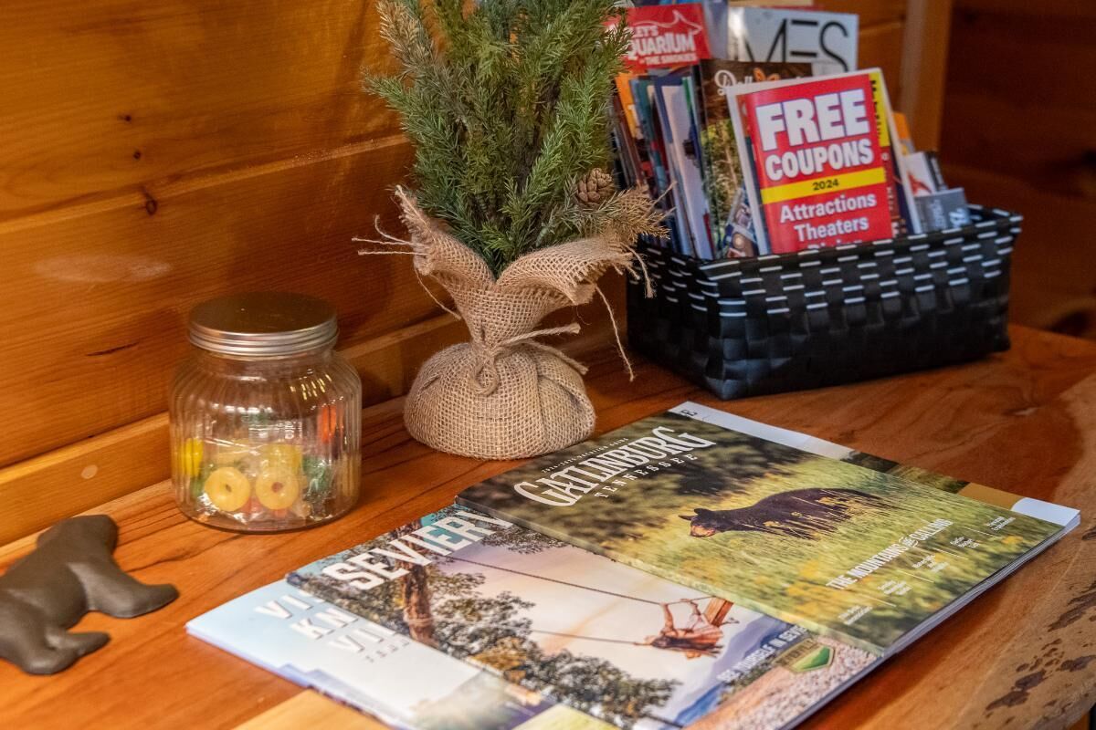 Ein Holztisch mit einem Buch, einer kleinen Pflanze, einer Süßigkeitengarne und einem Korb mit Gutscheinen.