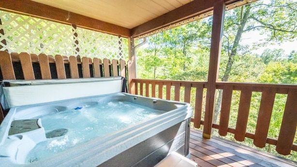 Een hottub op een houten terras met een houten leuning en een lattenwand.