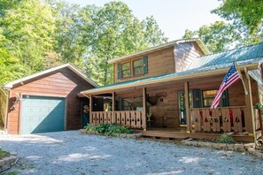 Eine zweigeschossige Holzhütte mit überdachter Veranda, einer Garage und einer US-amerikanischen Flagge.