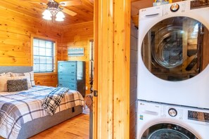 Ein Holzblockhaus-Innenraum mit Bett, Schminktisch und Waschmaschine.