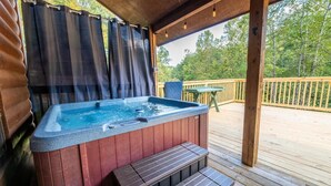 Een hottub op een houten terras met uitzicht op bomen.