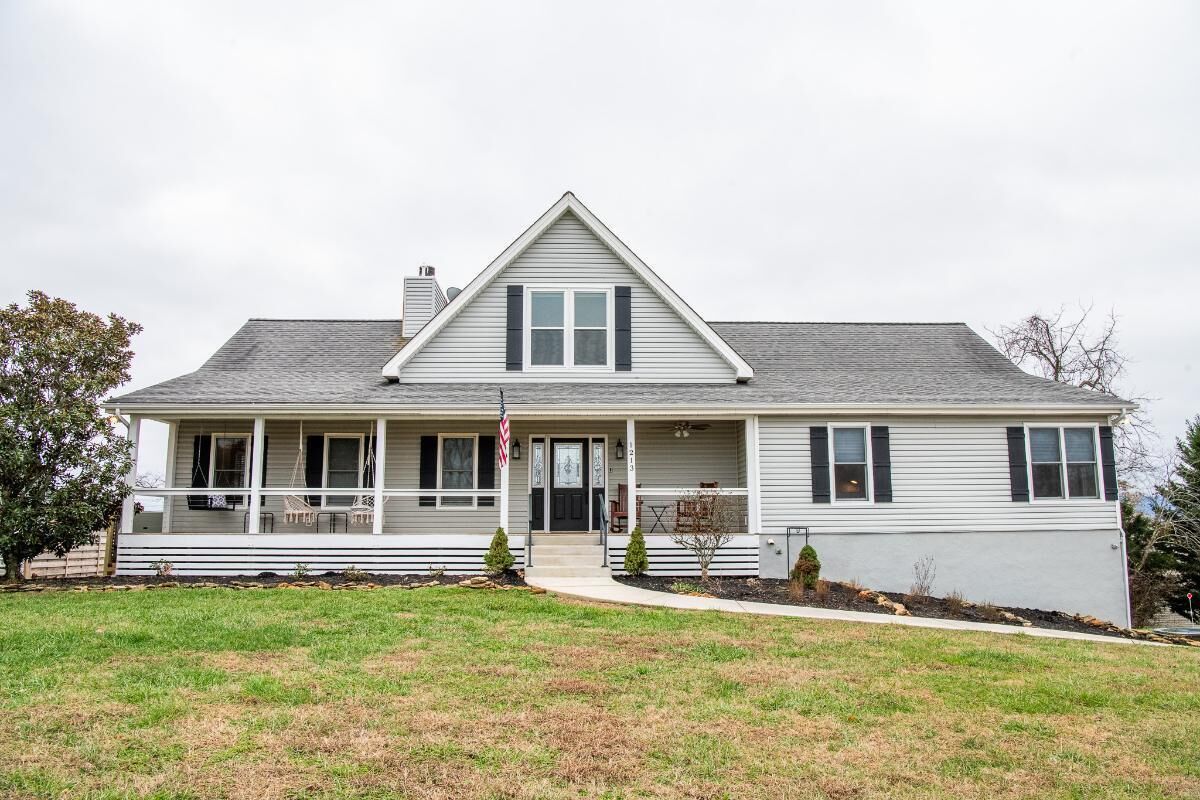 A two-story house with a front porch, a flag, and a small front yard.