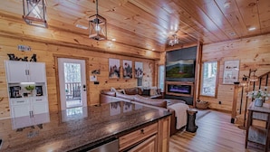 Ein Holzblockhaus-Innenraum mit Küche, Essbereich und Wohnzimmer.