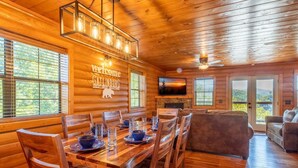 A wooden cabin interior with a dining area, a sofa, and a fireplace. - Ridge Vista (Gatlinburg)