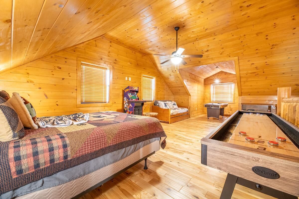 A cozy wooden cabin with a bed, a foosball table, and a small gaming console.