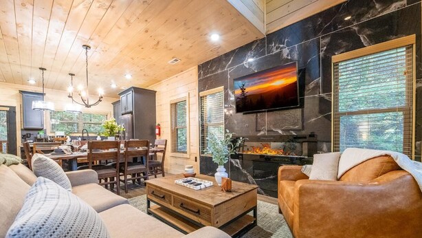 A cozy living room with a fireplace, wooden furniture, and a television mounted on the wall. - Valley Cove (Sevierville)