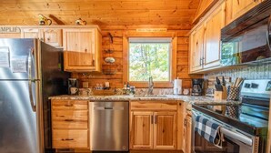 A wooden cabin kitchen with a stainless steel refrigerator, dishwasher, and oven. - Lasting Memories (Sevierville)