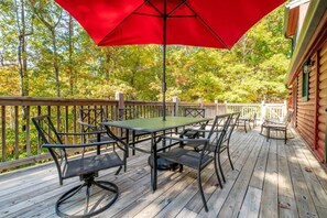A wooden deck with a table and chairs, surrounded by a wooden railing. - Lasting Memories (Sevierville)