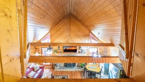 A wooden interior with a pitched ceiling, a fireplace, a sofa, and a dining area. - Lasting Memories (Sevierville)
