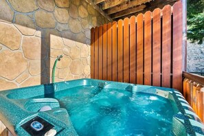 A hot tub with a stone wall and wooden fence in the background. - Windows to Heaven (Sevierville)