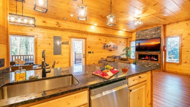 A wooden cabin interior with a kitchen, dining area, and fireplace. - Three Little Bears 2 (Gatlinburg)