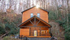 A log cabin with a front porch, a small deck, and a staircase leading to the entrance. - Three Little Bears 2 (Gatlinburg)
