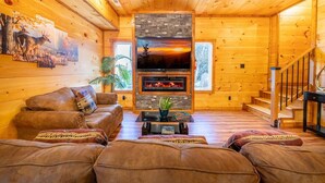 A log cabin interior with a fireplace, leather sofa, and a television. - Three Little Bears 2 (Gatlinburg)