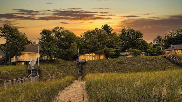A pathway leading to a beach house with a staircase and a flag. - The Beach Bungalow | Coastal Vibe | Private Beach! (West Olive)