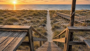A wooden boardwalk leading to a beach with a sunset in the background. - The Beach Bungalow | Coastal Vibe | Private Beach! (West Olive)