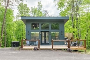 Eine moderne Holzhütte mit Terrasse, großen Fenstern und einer Eingangstür.