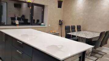 Una cucina moderna con una grande isola, mobili scuri e illuminazione a sospensione.