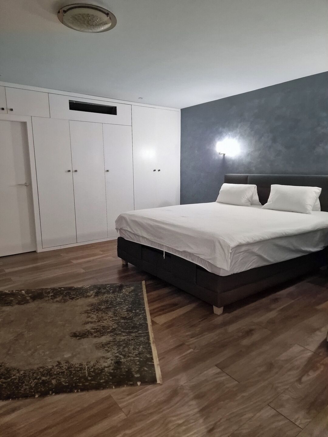Una camera da letto con un letto, un armadio e un tappeto.