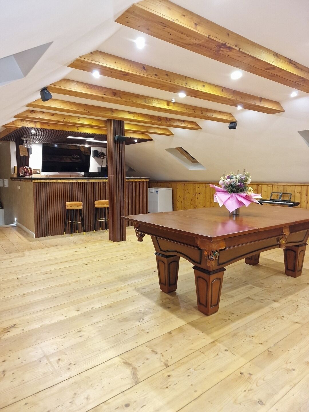 A spacious loft with a wooden dining table, a kitchen area, and a large window.