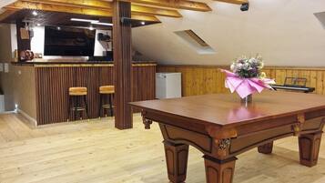 A spacious loft with a wooden dining table, a kitchen area, and a large window.