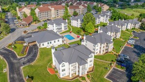 Un complejo residencial con varios edificios de apartamentos, piscina y zona de estacionamiento.