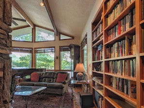 A spacious living area with a leather sofa, a coffee table, and a bookshelf filled with books. - Llyn Blaen House at Lake Junaluska (Lake Junaluska)