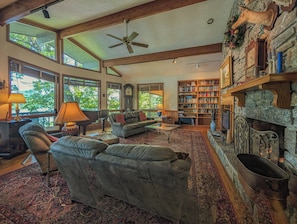 A spacious living room with a fireplace, bookshelves, and a large window. - Llyn Blaen House at Lake Junaluska (Lake Junaluska)