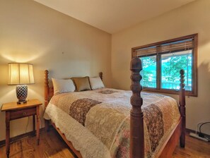 A bedroom with a four-poster bed, a bedside table with a lamp, and a window with blinds. - Llyn Blaen House at Lake Junaluska (Lake Junaluska)