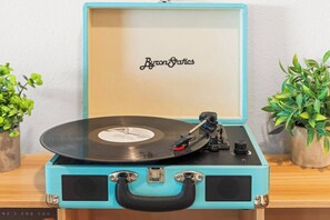 A turquoise record player with a vinyl record on it, placed on a wooden surface. - Ultimate Retreat|Pool~Spa~Pickleball~GameRoom~BBQ (Twentynine Palms)