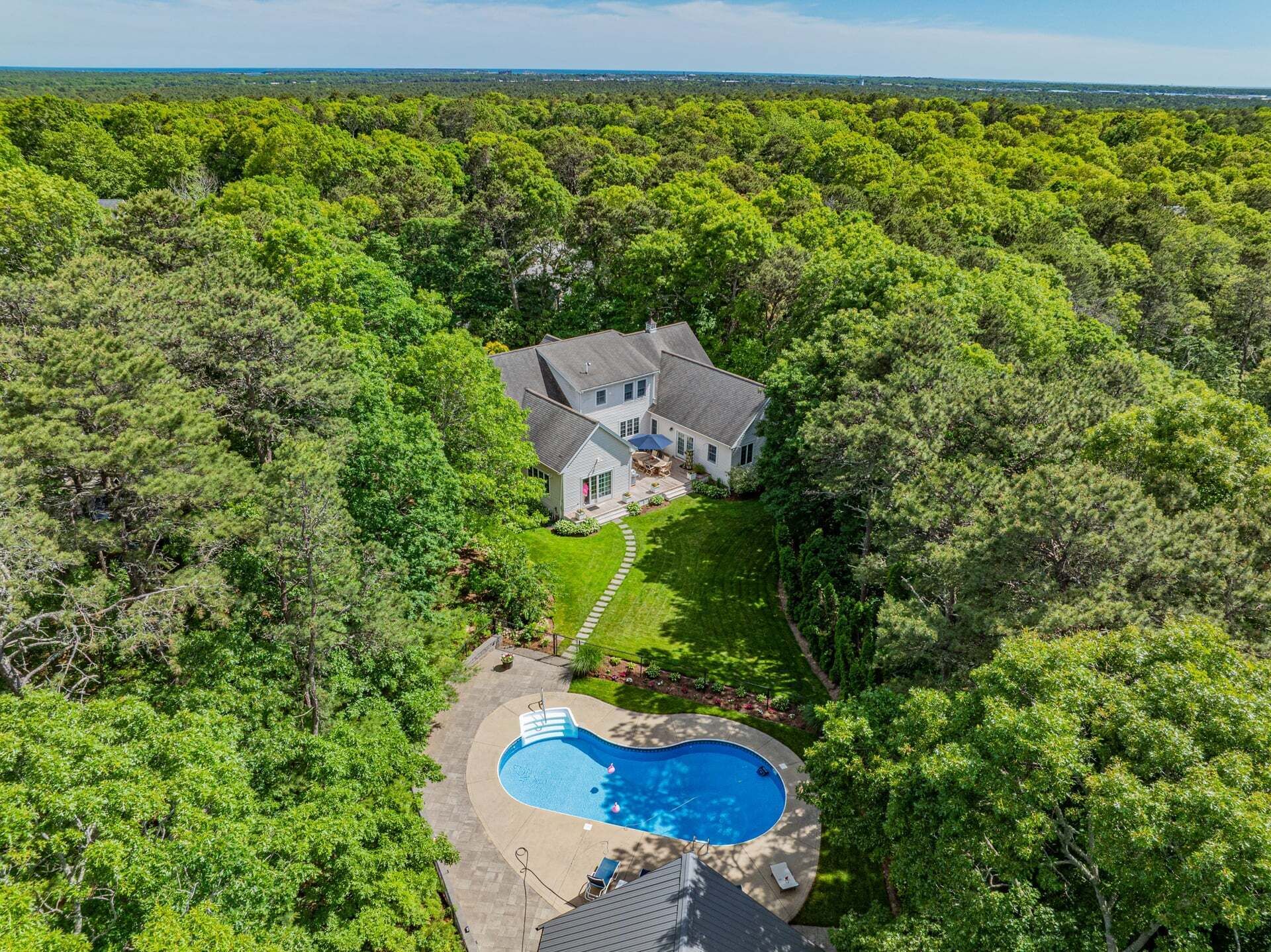 Una casa rodeada de un bosque frondoso con piscina.