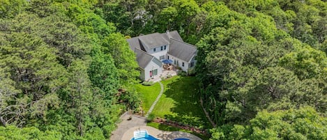 Una casa rodeada de un bosque frondoso con piscina.