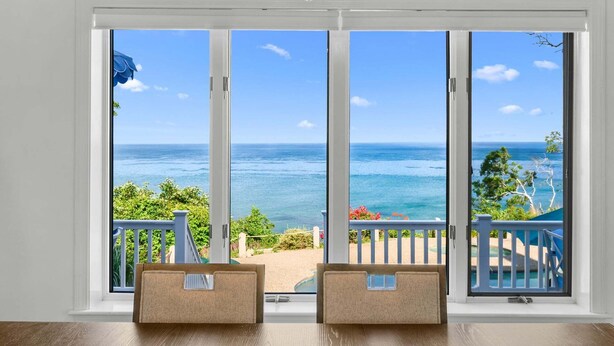 Una habitación con un amplio ventanal corredera que da a un balcón con vista al océano.