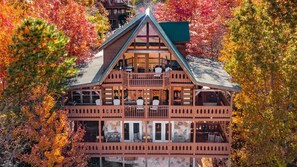A multi-story log cabin with balconies, surrounded by autumn foliage. - Lamp Post Lodge (Sevierville)
