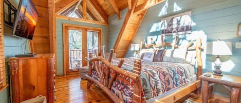 Un dormitorio de cabaña de troncos con cama, paredes de madera, televisor y ventana.