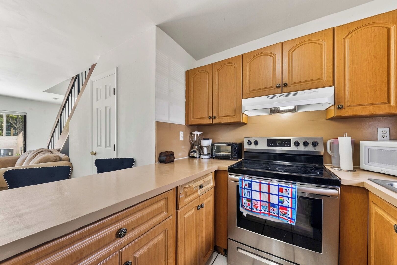 A kitchen with wooden cabinets, a stove, a microwave, and a coffee maker.