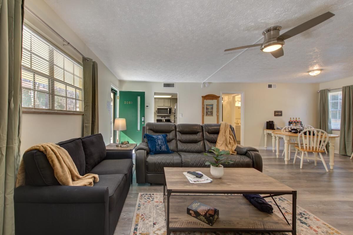 A living room with a sofa, coffee table, and a dining area with a table and chairs.