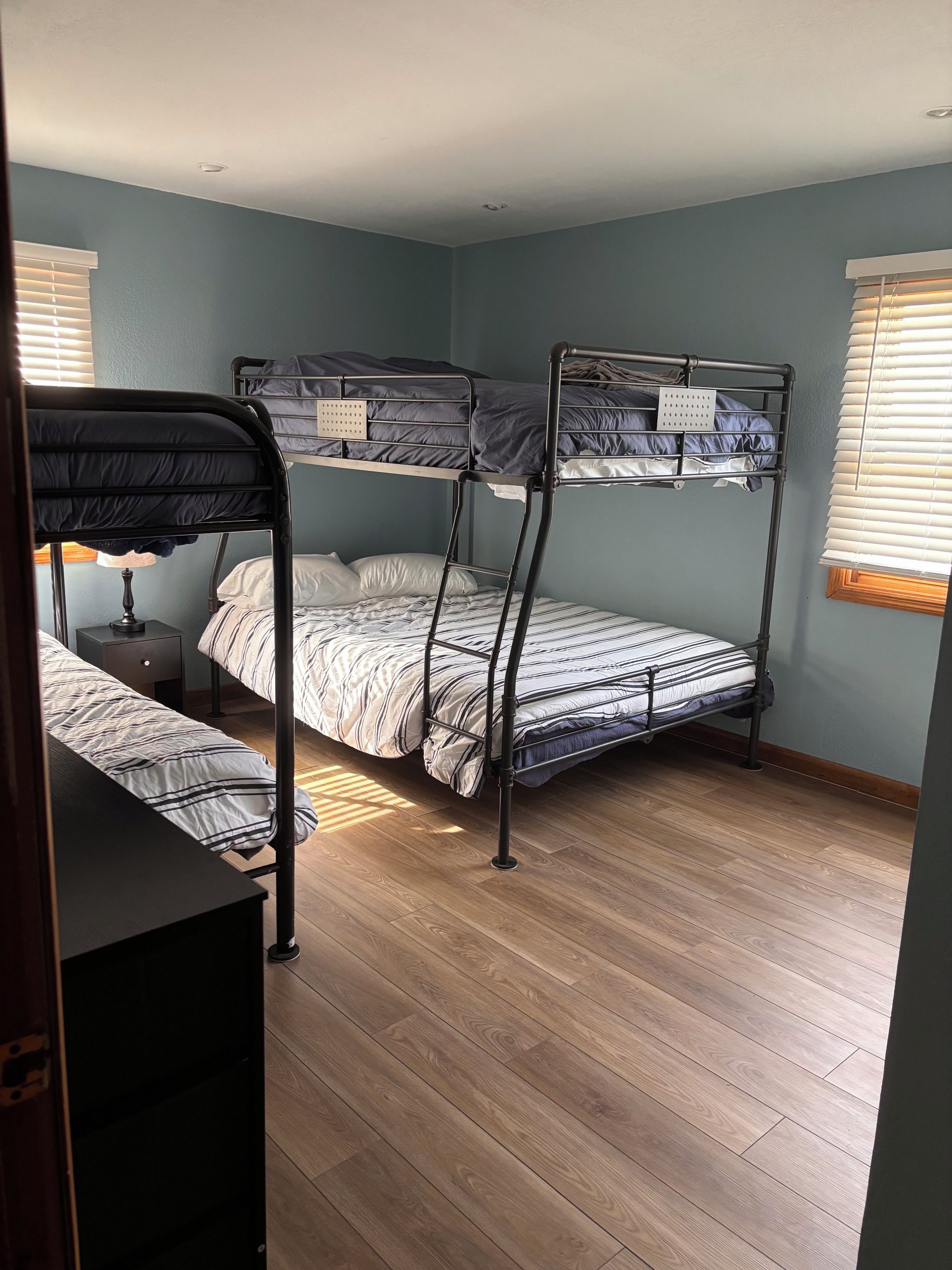 Une chambre avec un lit superposé, un plancher en bois, un bureau et une lampe.