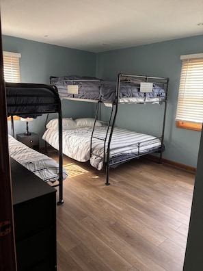 Habitación con literas, piso de madera, escritorio y lámpara.