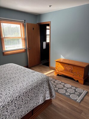 A bedroom with a bed, a dresser, a window with blinds, and a door leading to a closet.