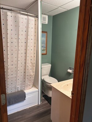 A bathroom with a shower curtain, toilet, and sink.
