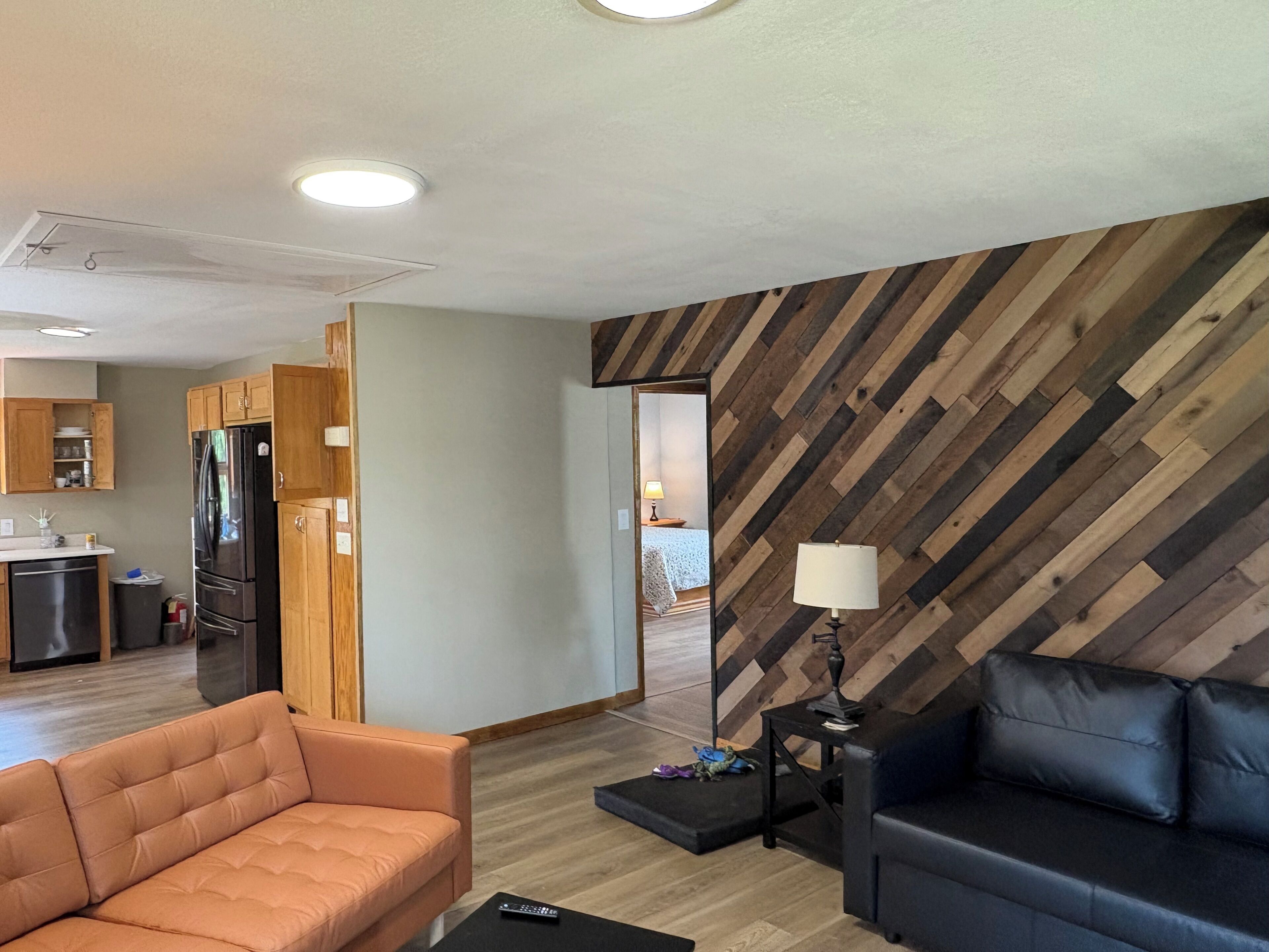 Ein modernes Wohnzimmer mit einer Couch, einem Couchtisch, einer Lampe und einem Essbereich mit einem Kühlschrank.
