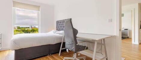 Un dormitorio con cama, escritorio y silla.