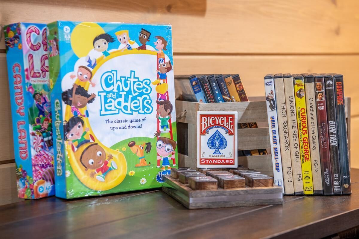 A board game, a DVD collection, and a set of playing cards on a wooden surface.