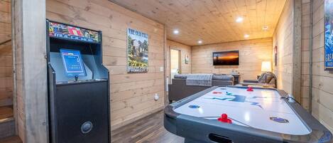 A wooden interior with a pool table, a foosball table, and a billiards table.