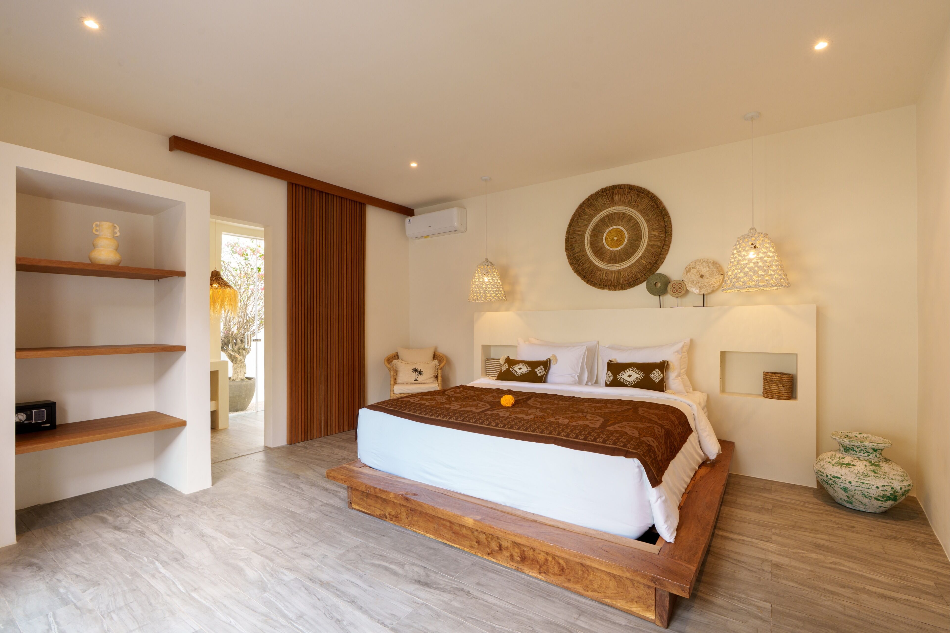 Un dormitorio con una cama grande, cabecera de madera y vista a un jardín.